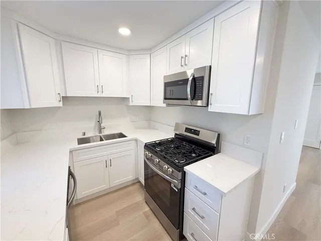 a kitchen with stainless steel appliances granite countertop white cabinets a stove top oven a sink and dishwasher
