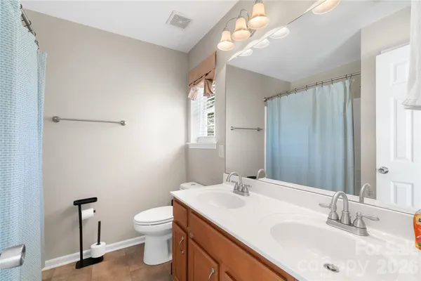 a bathroom with a toilet a sink a mirror and a window