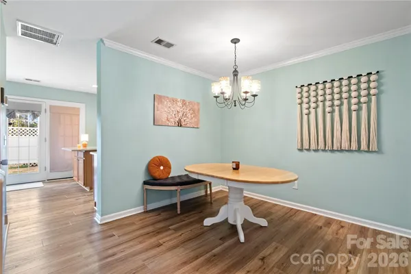 a dining room with wooden floor a chandelier a wooden table and chairs