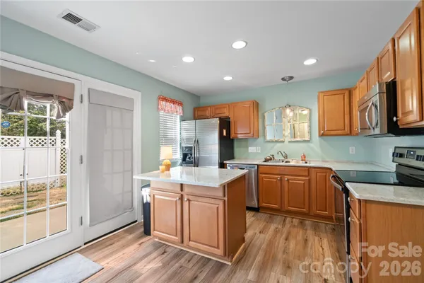 a kitchen with stainless steel appliances granite countertop a stove a sink dishwasher and a refrigerator with wooden floor