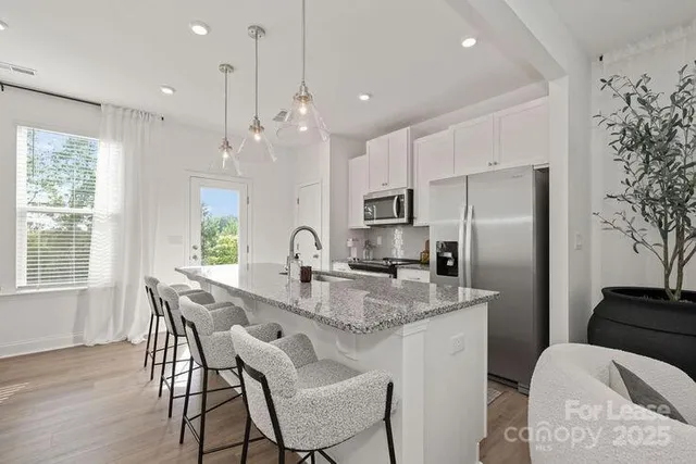 a kitchen with stainless steel appliances granite countertop a kitchen island hardwood floor a dining table and chairs