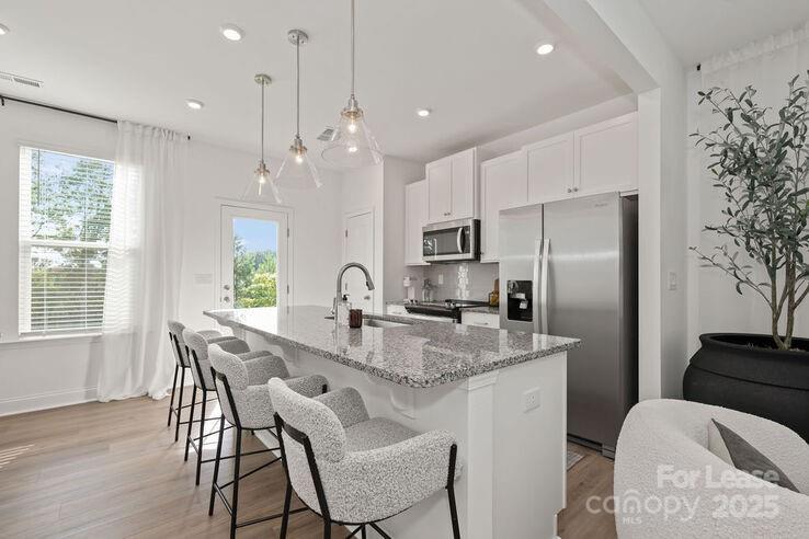 a kitchen with stainless steel appliances granite countertop a kitchen island hardwood floor a dining table and chairs