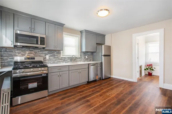 a kitchen with wooden floors and stainless steel appliances