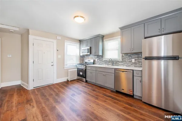 a kitchen with a refrigerator a sink and dishwasher with wooden floor