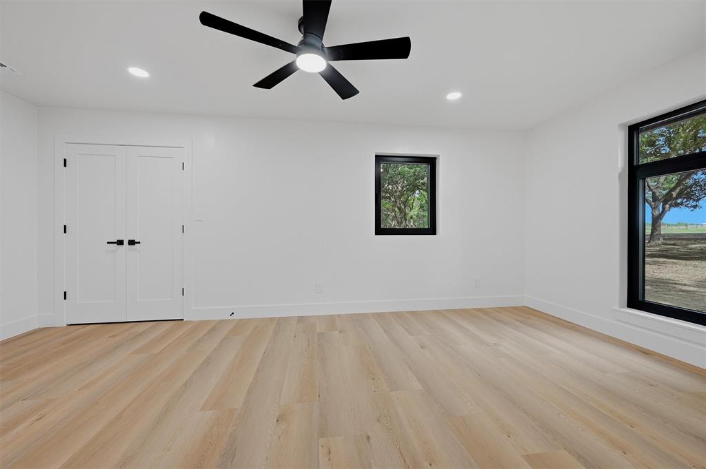 410 Arkansas Road Sadler, TX 76264 - Photo 21 of 40 Spacious interior room featuring light wood-finish flooring, white walls, and a black ceiling fan