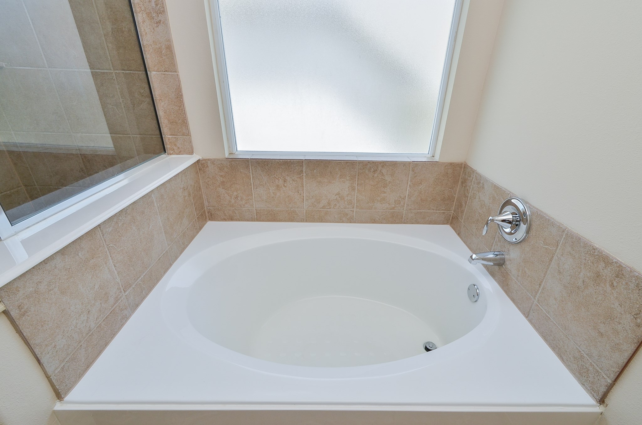 25135 Ginger Ranch Drive Katy, TX 77494 - Photo 23 of 32 Primary bath: A soaking tub with tile surround and frosted window offers a relaxing bathing space with added privacy.