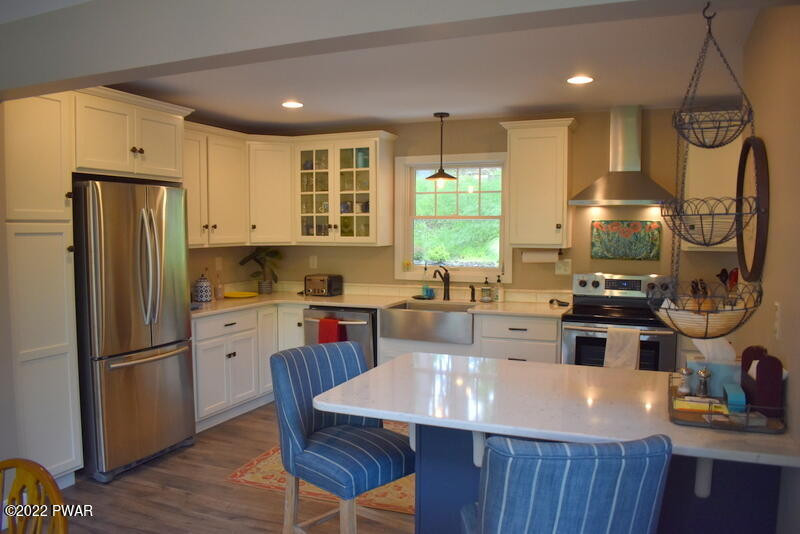 549 Finn Swamp Road Lakeville, PA 18438 - Photo 7 of 35 a kitchen with stainless steel appliances granite countertop a refrigerator a sink dishwasher a stove and a dining table with wooden floor
