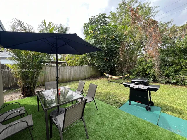 a view of a table and chairs under an umbrella in backyard