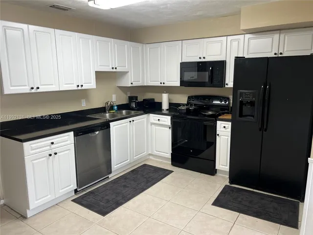 a kitchen with granite countertop a refrigerator and a stove top oven