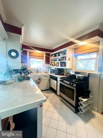 a kitchen with stainless steel appliances granite countertop a stove a sink dishwasher and white cabinets with wooden floor