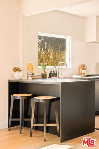 a view of a kitchen with kitchen island a large window a sink stainless steel appliances and cabinets