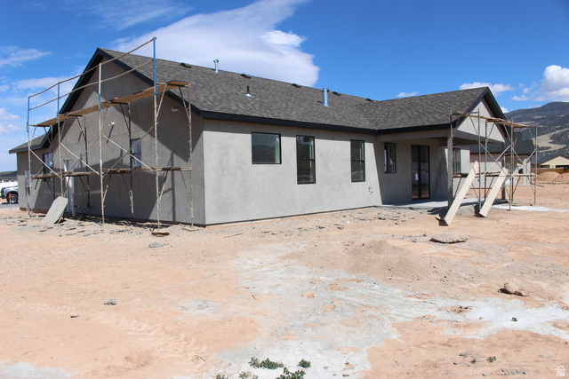 4933 East Remington Road Cedar City, UT 84721 - Photo 26 of 33 Newly constructed residence featuring a gray stucco exterior, dark shingle roof, and black-framed windows