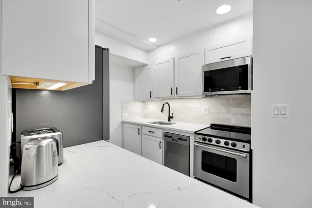 a kitchen with stainless steel appliances a stove a sink and a microwave