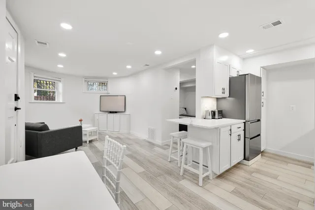 a large white kitchen with stainless steel appliances kitchen island granite countertop a refrigerator and cabinets