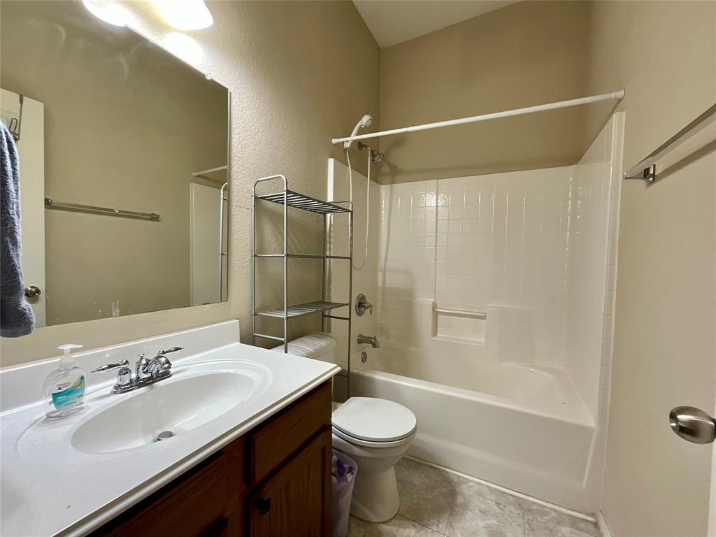 14044 Fontana Road Roanoke, TX 76262 - Photo 12 of 14 Bathroom featuring a vanity with a white countertop and integrated sink, chrome faucet, wall-mounted mirror, and a shower/tub combination with a white surround