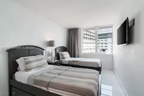 a bedroom with a bed and a flat tv screen on a dresser