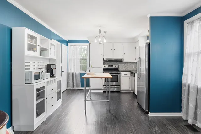 a kitchen with stainless steel appliances a stove a sink a refrigerator cabinets and wooden floor