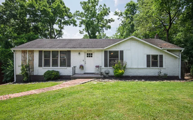 a view of a house with a yard and table and chairs under an umbrella