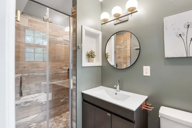 a bathroom with a sink a mirror a vanity and a shower