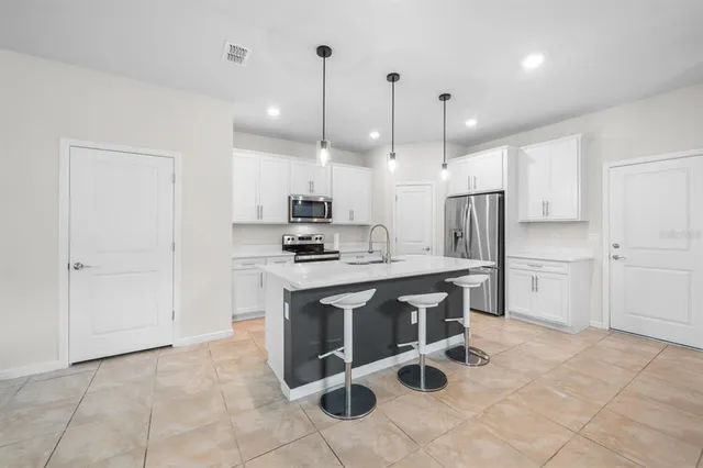 a kitchen with kitchen island a stove a table and chairs