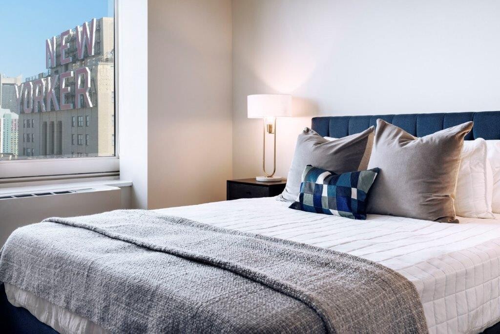 315 West 33rd Street, Unit 27F Manhattan, NY 10001 - Photo 5 of 13 a large bed sitting in a bedroom next to a window