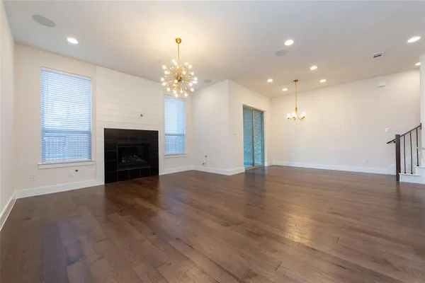 an empty room with wooden floor fireplace and staircase