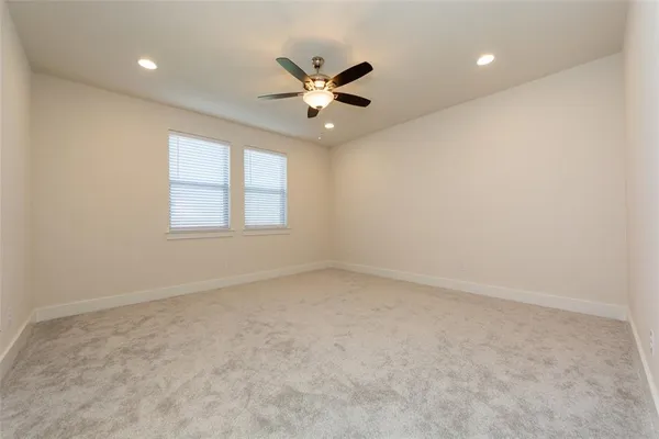 an empty room with windows and ceiling fan