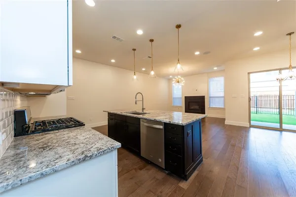 a kitchen with stainless steel appliances granite countertop a sink a stove and a wooden floor