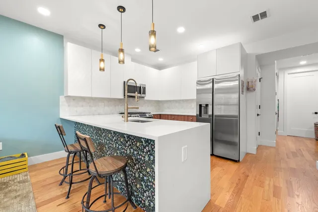a kitchen with stainless steel appliances kitchen island a table chairs in it and wooden floors