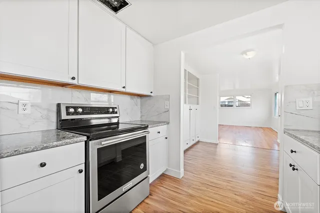a kitchen with granite countertop a stove and white cabinets