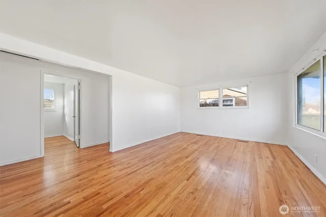 an empty room with wooden floor and windows