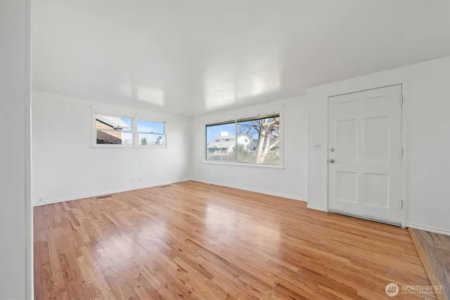 a view of an empty room with wooden floor and a window