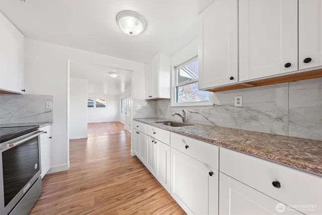 a kitchen with granite countertop white cabinets and a wooden floor