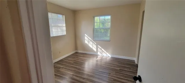 a view of an empty room with wooden floor and a window