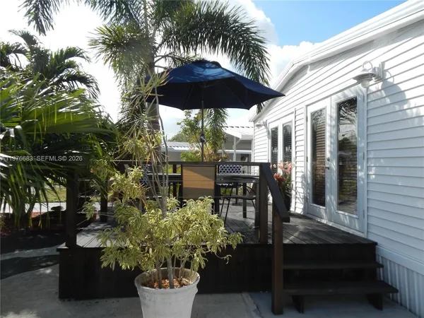 a patio with table and chairs and potted plants