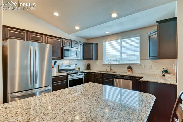 a kitchen with granite countertop a refrigerator stove top oven and sink