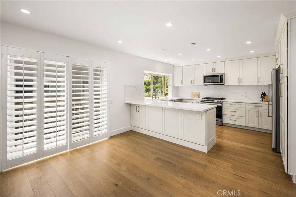 8 Moon Shadow, Unit 8 Irvine, CA 92603 - Photo 17 of 42 a kitchen with stainless steel appliances granite countertop a stove a sink and white cabinets with wooden floor