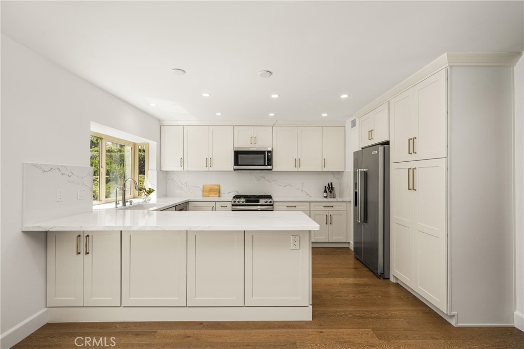 8 Moon Shadow, Unit 8 Irvine, CA 92603 - Photo 18 of 42 a kitchen with stainless steel appliances granite countertop a refrigerator a sink dishwasher a stove oven and white countertops with wooden floor