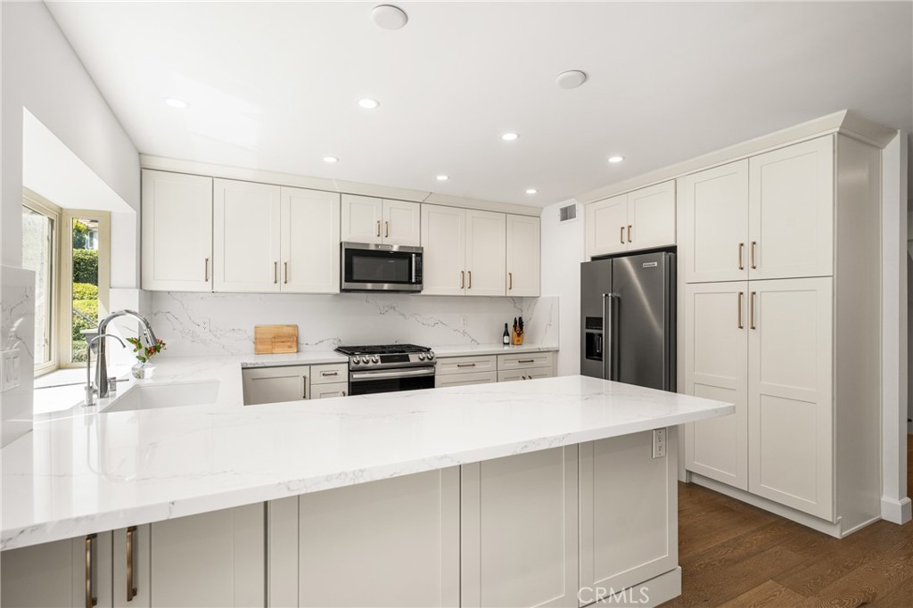 8 Moon Shadow, Unit 8 Irvine, CA 92603 - Photo 19 of 42 a kitchen with stainless steel appliances a refrigerator sink stove and white cabinets