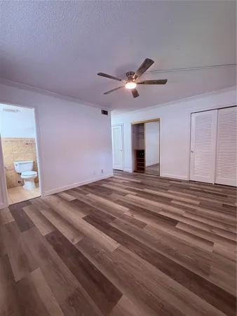 a view of empty room with wooden floor and fan