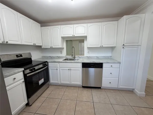 a kitchen with granite countertop white cabinets and stainless steel appliances