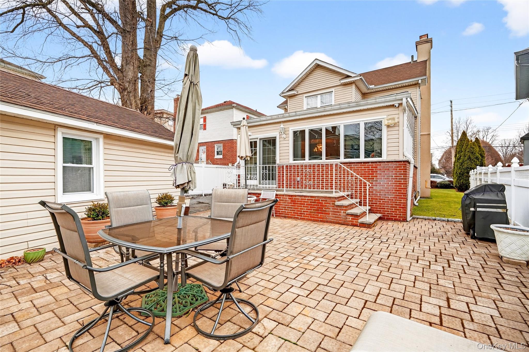 3334 Country Club Road Bronx, NY 10465 - Photo 46 of 49 Back of property featuring outdoor dining space, a patio, a chimney, brick siding, and roof with shingles