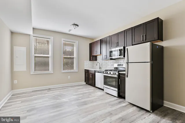 a kitchen with stainless steel appliances granite countertop a refrigerator stove a sink dishwasher and wooden cabinets with wooden floor