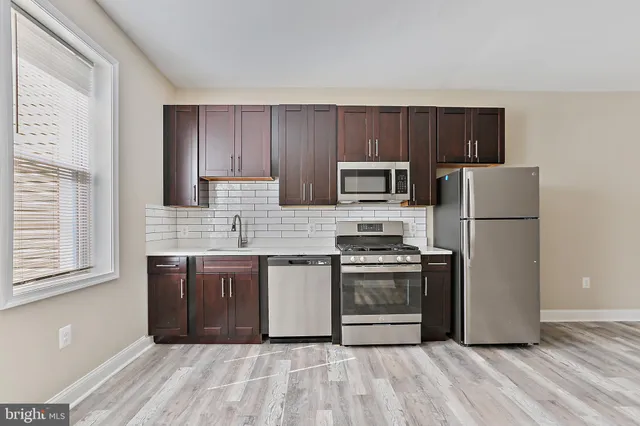 a kitchen with a refrigerator sink and wooden cabinets