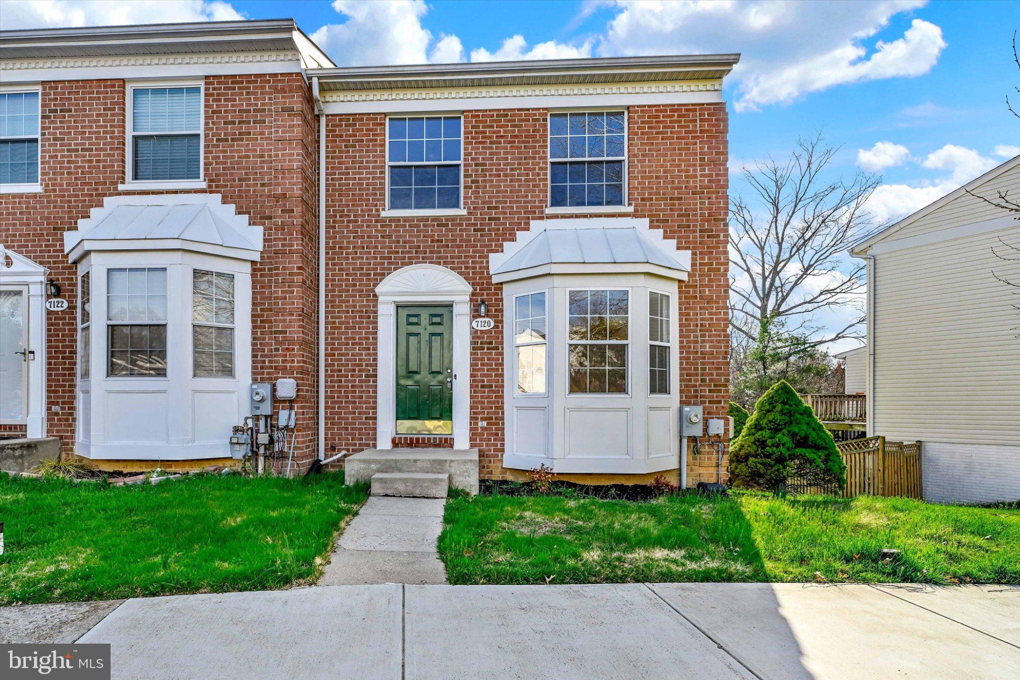 Charming brick end of row townhouse with greenery.