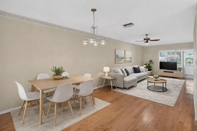 a view of an empty room with wooden floor and a kitchen