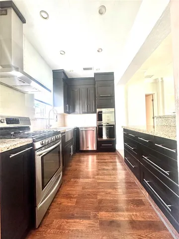 a kitchen with stainless steel appliances granite countertop a stove a sink and a microwave