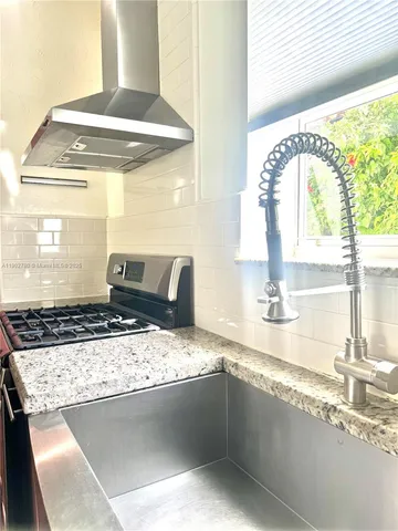 a kitchen with stainless steel appliances kitchen island granite countertop a table and a sink