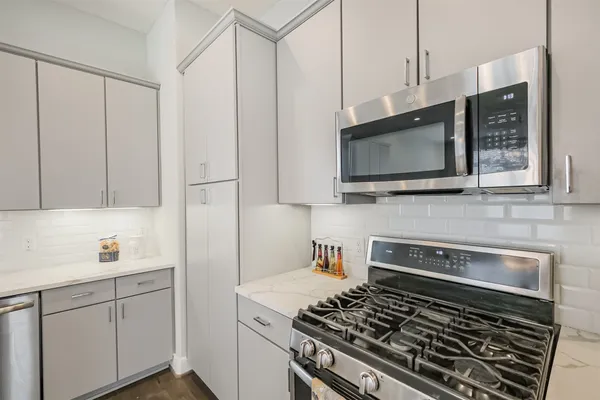 a kitchen with stainless steel appliances a stove microwave and sink