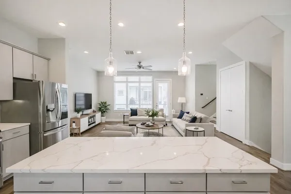 a view of a kitchen with kitchen island stainless steel appliances a refrigerator a sink dishwasher a oven and a dining table with wooden floor